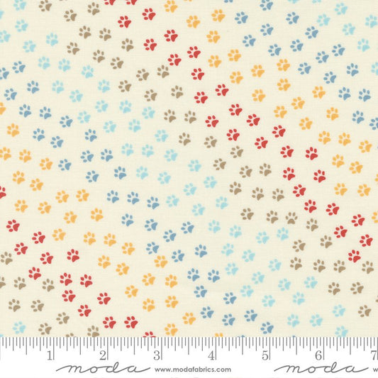 Cream fabric with rainbow colored paw prints on it.